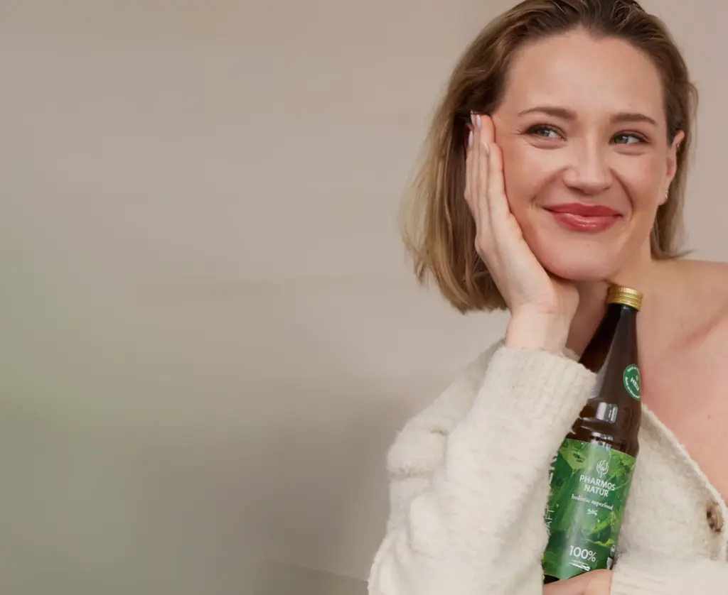 Zufriedene Frau mit einer Aloe Vera Bio Ursaft Flasche von Pharmos Natur im Arm