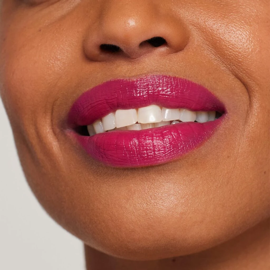 Frau mit dunklem Hautton, auf den Lippen den ColorLuxe Lippenstift von janeiredale in der Farbe Peony - bei Claresco Cosmetic kaufen